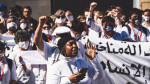 Joukko mielenosoittajia Sharm el-Sheikhissä valkoisten iskulauselakanoiden kanssa. Etualalla turbaanipäinen nainen.