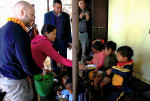 Joonas Könttä jaka vihreästä ämpäristä kauhalla kouluruokaa pienille nepalilaisille koululaisille.