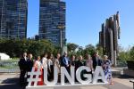 Pihalla suuren kirjaimet # UNGA eli lyhenne yleiskokouksesta ja kirjainten takana joukko suomalaisia, taaempana pilvenpiirtäjiä