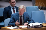vaaleahiuksinen mies kravatti kaulassa pitää puheenvuoroa, pöydällä kyltti Europea Union
