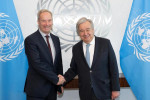 Olof Skoog ja pääsihteeri António Guterres kättelevät YK:n lippujen edessä