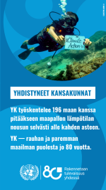 YK työskentelee 196 maan kanssa pitääkseen maapallon lämpötilan nousun selvästi alle kahden asteen. kuvassa sukeltaja koralliriutan äärellä pitää lappua climate action