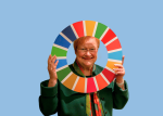 Tarja Halonen kurkkaa kestävän kehityksen tavoitteita kuvaavan värikkään rinkulan keskeltä